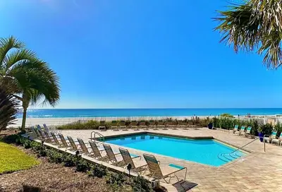 a swimming pool with chairs and the beach at Pelican Walk 1012 in Panama City Beach