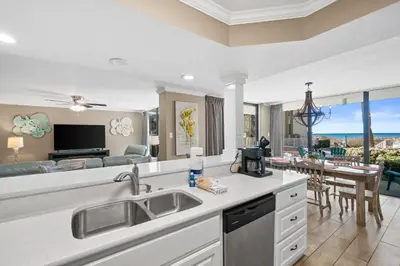 a kitchen with a sink and a living room at Pelican Walk 101 in Panama City Beach