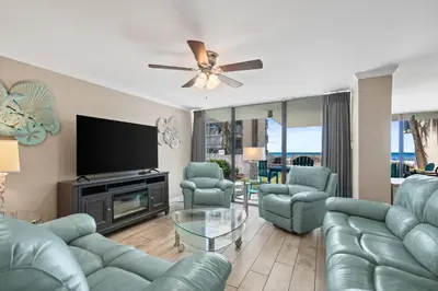 a living room with blue furniture and a flat screen tv at Pelican Walk 101 in Panama City Beach