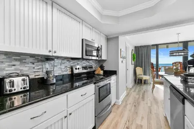 a kitchen with white cabinets and black counter tops at Pelican Walk 308 in Panama City Beach