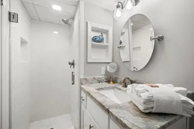a white bathroom with a sink and a mirror at Pelican Walk 309 in Panama City Beach