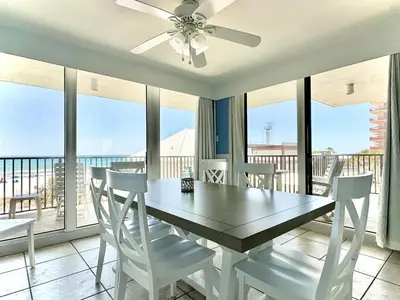 a dining room with a table and chairs and windows at Pelican Walk 312 in Panama City Beach