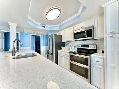 a kitchen with white cabinets and stainless steel appliances at Pelican Walk 312 in Panama City Beach