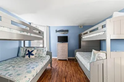 a bedroom with two bunk beds and a tv at Pelican Walk 312 in Panama City Beach