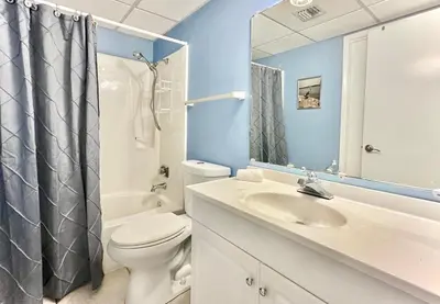 a bathroom with a toilet and a sink and a mirror at Pelican Walk 312 in Panama City Beach