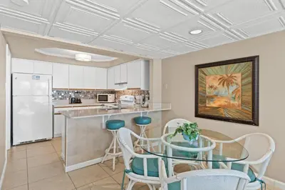 a kitchen with a table and chairs and a refrigerator at Pelican Walk 204 in Panama City Beach