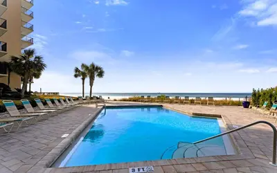 a swimming pool next to a beach with palm trees at Pelican Walk 204 in Panama City Beach