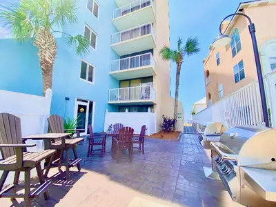 a patio with chairs and tables and a building at Pelican Walk 204 in Panama City Beach