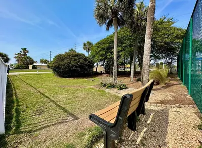a wooden bench sitting in a park with palm trees at Pelican Walk 204 in Panama City Beach