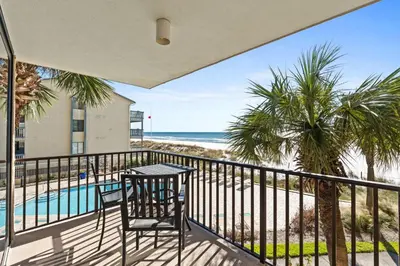 a balcony with a table and chairs and the beach at Pelican Walk 204 in Panama City Beach