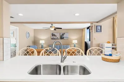 a kitchen with a sink and a living room at Pelican Walk 401 in Panama City Beach