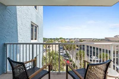 a balcony with two chairs and a view of a street at Pelican Walk 401 in Panama City Beach
