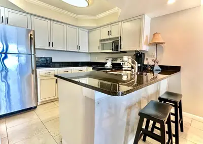 a kitchen with white cabinets and a refrigerator at Pelican Walk 102 in Panama City Beach