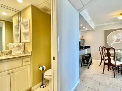a bathroom with a toilet and a dining room at Pelican Walk 102 in Panama City Beach