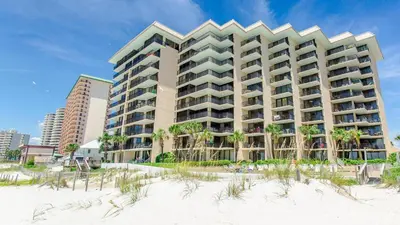 a hotel on the beach with palm trees at Pelican Walk 102 in Panama City Beach