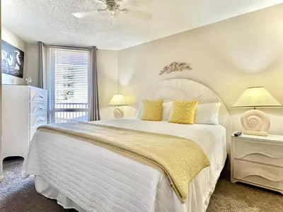 a bedroom with a large white bed with yellow pillows at Pelican Walk 404 in Panama City Beach