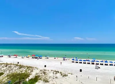 a beach with umbrellas and people on the beach at Pelican Walk 404 in Panama City Beach