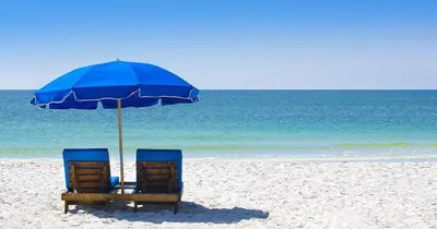 two chairs and an umbrella on a beach at Pelican Walk 403 in Panama City Beach