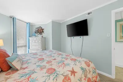 a bedroom with a bed and a flat screen tv at Pelican Walk 209 in Panama City Beach