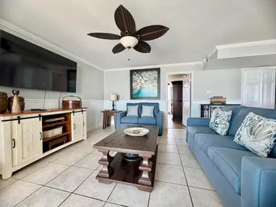 a living room with a blue couch and a ceiling fan at Pelican Walk 512 in Panama City Beach