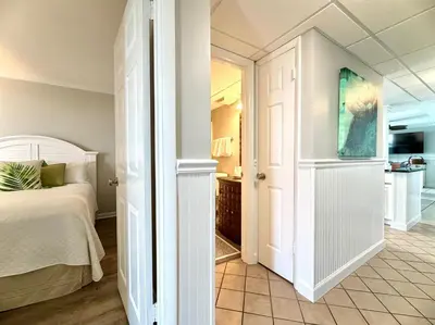 a white bedroom with a bed and a bathroom at Pelican Walk 512 in Panama City Beach