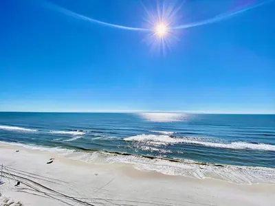 a beach with the sun in the sky and the ocean at Pelican Walk 504 in Panama City Beach