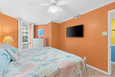 a bedroom with a bed and a flat screen tv at Pelican Walk 210 in Panama City Beach