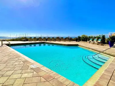 a swimming pool with blue water and chairs at Pelican Walk 210 in Panama City Beach