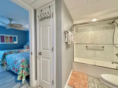 a bathroom with a shower and a bed and a tub at Pelican Walk 506 in Panama City Beach