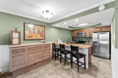 a kitchen with green walls and a counter with bar stools at Pelican Walk 211 in Panama City Beach