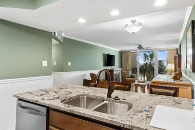 a kitchen with a sink and a living room at Pelican Walk 211 in Panama City Beach
