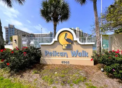 a sign for a pelican walk sign with palm trees at Pelican Walk 211 in Panama City Beach