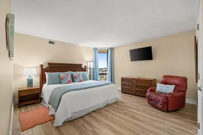 a bedroom with a bed and a chair and a television at Pelican Walk 601 in Panama City Beach