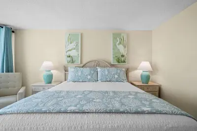 a bedroom with a bed with blue pillows and two lamps at Pelican Walk 601 in Panama City Beach