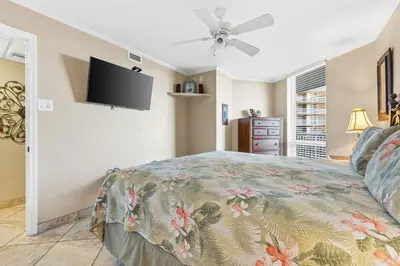 a bedroom with a bed and a flat screen tv at Pelican Walk 402 in Panama City Beach