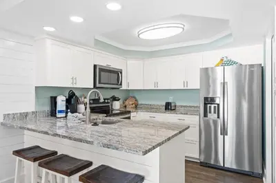 a kitchen with white cabinets and a stainless steel refrigerator at Pelican Walk 611 in Panama City Beach