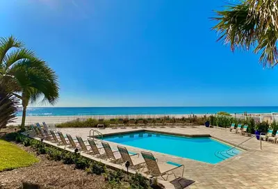 a swimming pool with chairs and the beach at Pelican Walk 611 in Panama City Beach