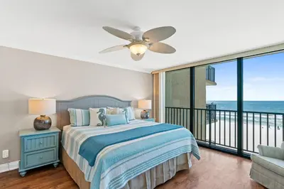 a bedroom with a bed and a balcony with the ocean at Pelican Walk 408 in Panama City Beach