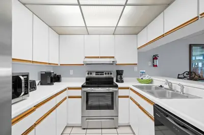 a kitchen with white cabinets and a stove and sink at Pelican Walk 902 in Panama City Beach