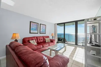a living room with a red couch and a glass table at Pelican Walk 902 in Panama City Beach