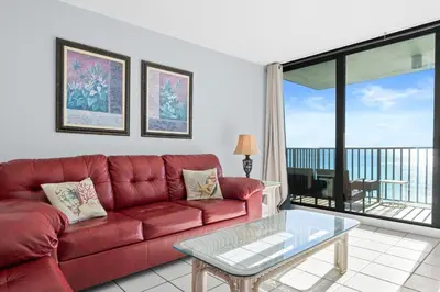 a living room with a red couch and a balcony at Pelican Walk 902 in Panama City Beach