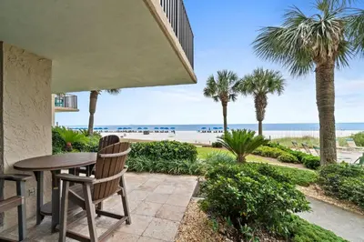 a patio with a table and chairs and the beach at Pelican Walk 108 in Panama City Beach