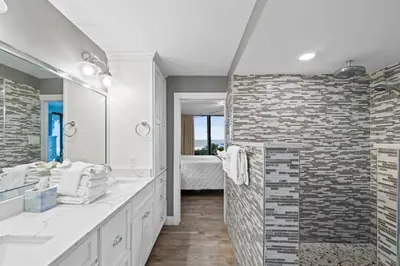a bathroom with a large mirror and a brick wall at Pelican Walk 108 in Panama City Beach