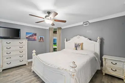 a bedroom with a white bed and a ceiling fan at Pelican Walk 108 in Panama City Beach