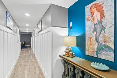 a hallway with blue walls and a painting of a mermaid at Pelican Walk 108 in Panama City Beach