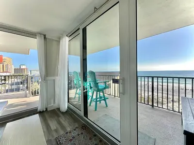 a room with a balcony with a view of the ocean at Pelican Walk 501 in Panama City Beach