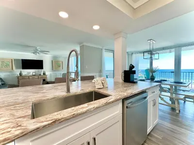 a kitchen with a sink and a living room at Pelican Walk 501 in Panama City Beach