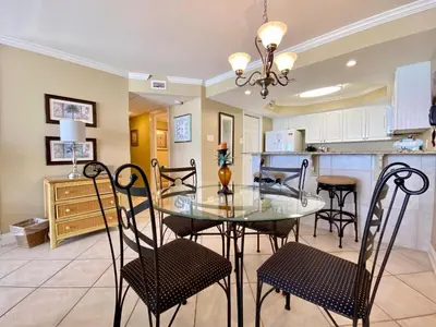 a dining room and kitchen with a glass table and chairs at Pelican Walk 502 in Panama City Beach