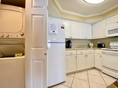 a kitchen with white cabinets and a white refrigerator at Pelican Walk 502 in Panama City Beach