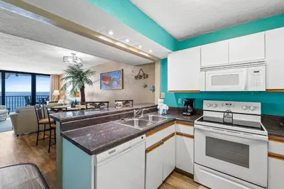 a kitchen with white appliances and a dining room at Pelican Walk 1009 in Panama City Beach